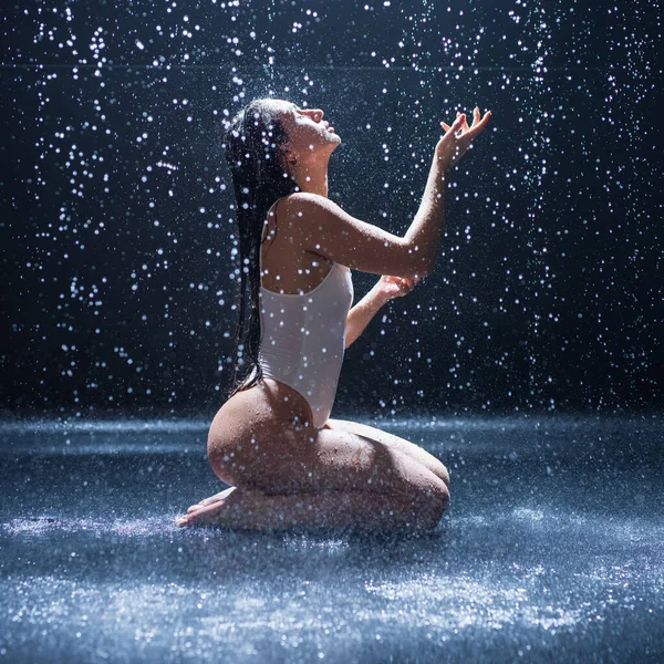 Mujer en bikini captura gotas de lluvia en un estudio oscuro — Foto de Stock