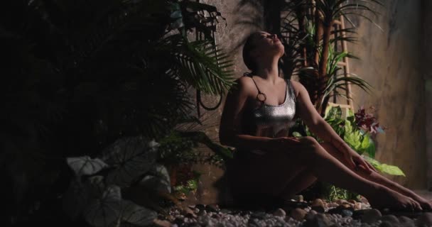 Жінка в бікіні сидить під тропічним душем, повільний рух — стокове відео