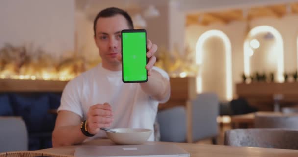Ο άνθρωπος δείχνει πράσινο chromakey οθόνη στο καφέ — Αρχείο Βίντεο