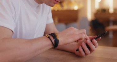 Yakından tanınmayan bir adam bir kafede telefon kullanıyor.