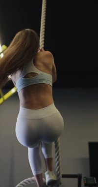 Genç bir kadın ipe tırmanıyor.