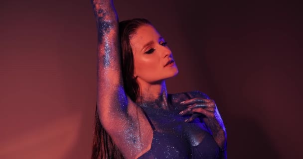 Frau mit blauem Glitzer am Körper posiert im Atelier — Stockvideo