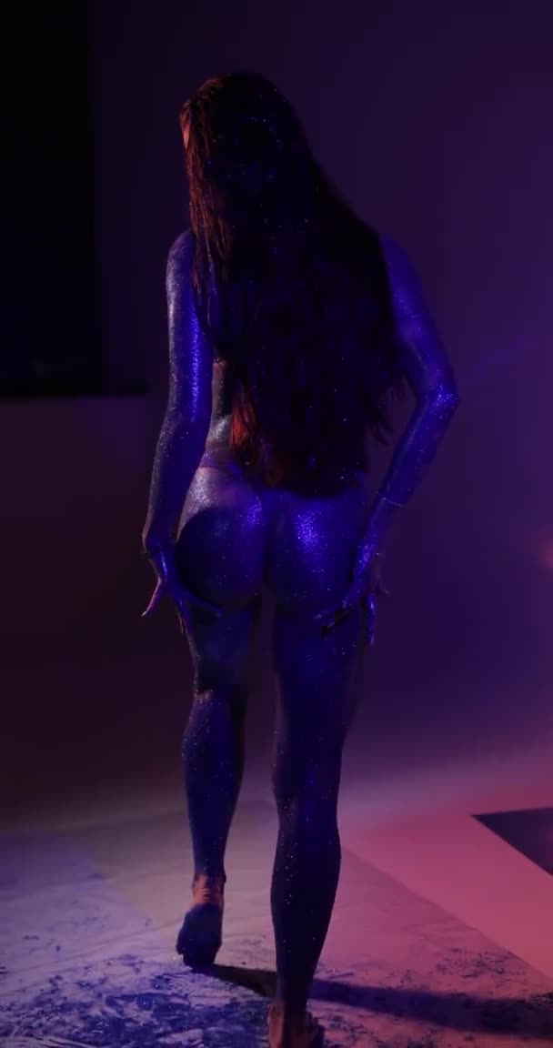 Kvinna med blått glitter poserar i en studio, vertikal video — Stockvideo