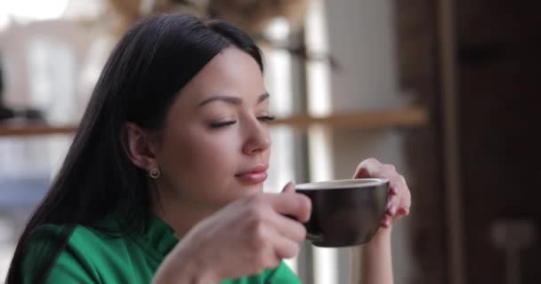 Женщина пьет кофе сидя в кафе — стоковое видео