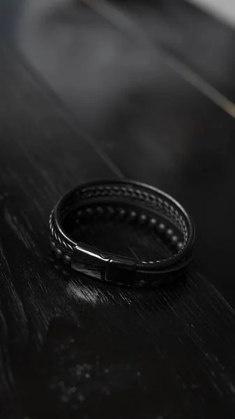 Pulseira masculina de couro preto em uma mesa escura — Fotografia de Stock