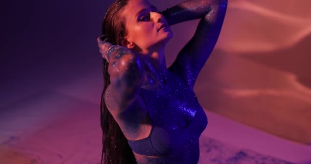 Женщина с синими блестками позирует в студии — стоковое видео