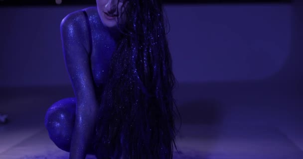 Kvinna med blått glitter poserar i en studio — Stockvideo