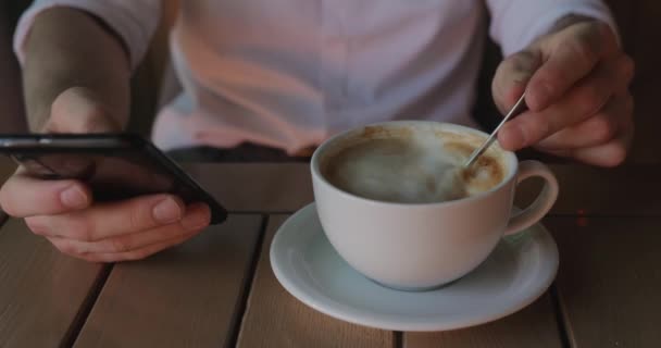 Hombre de negocios irreconocible usando el teléfono mientras bebe café — Vídeos de Stock