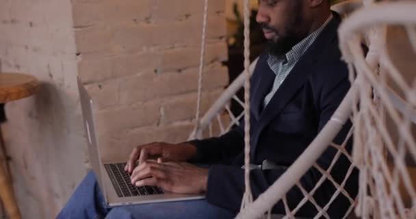Afrikalı işadamı kafedeki bilgisayar başında dinleniyor. — Stok video