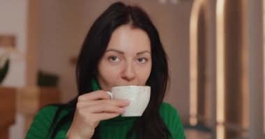 Kafede oturan bir kadın kahve içer.