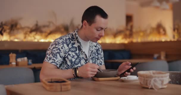 Hombre adicción a Internet utiliza el teléfono mientras come alimentos — Vídeo de stock