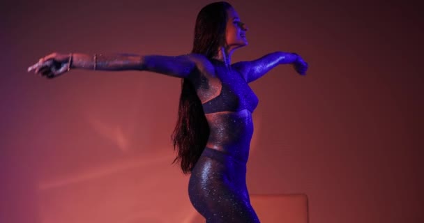 Женщина с синими блестками на теле позирует в студии — стоковое видео