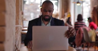 Afrikalı işadamı kafede bilgisayarla çalışıyor.