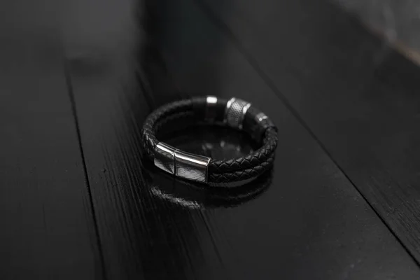 Pulsera masculina de cuero negro en un escritorio oscuro — Foto de Stock