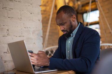 Kafede oturan akıllı telefonu kullanan Afrikalı işadamı