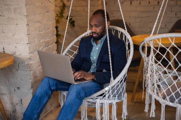 Afrikanischer Geschäftsmann ruht mit Laptop in Café — Stockfoto