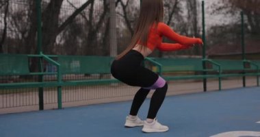 Sportif kadın spor bacakları ve lastik bantlarla çalışıyor.