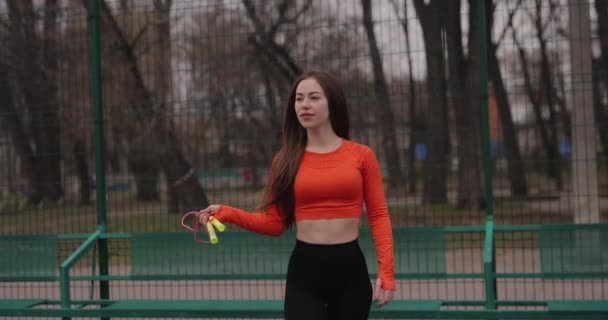 Donna sexy sportiva che trasporta una corda da salto in un parco — Video Stock