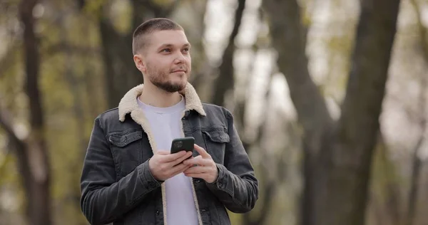Hombre Sonriente Usar Teléfono Inteligente Caminando Parque Día Primavera —  Fotos de Stock