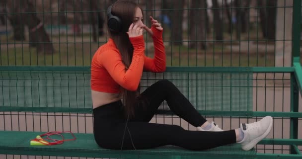 在室外用耳机听音乐的胖女人 — 图库视频影像