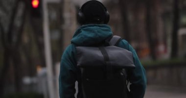 Arkadan bakan adam şehirde büyük kulaklıklarla elleri ısıtıyor.