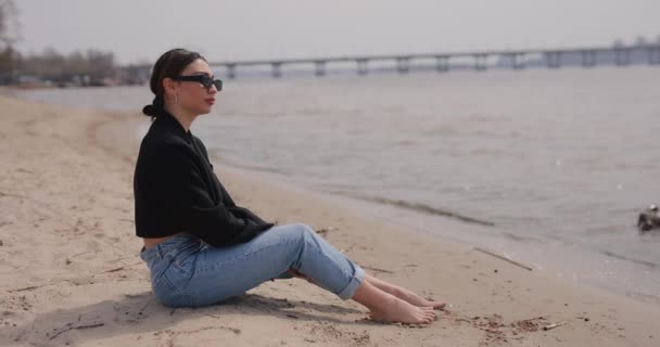Kvinnan sitter på stranden och slappnar av — Stockvideo
