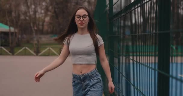 Cute girl walks on a stadium in a park — Stock Video