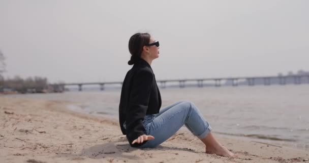 Γυναίκα κάθεται στην παραλία και χαλαρώνει — Αρχείο Βίντεο