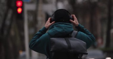 Arka plandaki adam şehirde büyük kulaklık takıyor.