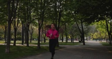 Yaz parkında kulaklıklarla koşan güzel bir kadın müzik dinliyor.