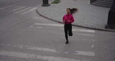 Sporty woman jogging in the city crossing road on a zabra