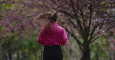 Arka plan kadını yaz parkında ağır çekimde koşuyor.