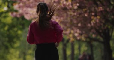 Arka plan kadını yaz parkında ağır çekimde koşuyor.