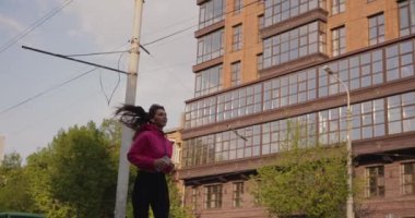 Kulaklıklarıyla şehirde koşan güzel ve sportif bir kadın müzik dinliyor.