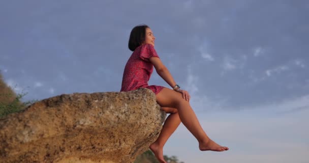 Onnellinen Nainen Istuu Kivellä Vasten Taivaan Tausta Katselee Auringonlaskua — kuvapankkivideo