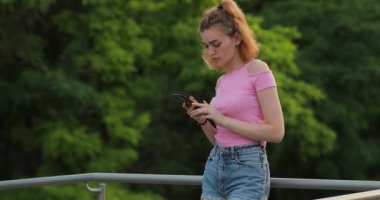 Parkta cep telefonu kullanan bir kadın web sitesinde uygulamayı izliyor