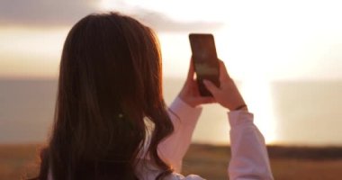 Kadın, deniz batımının güzel bir fotoğrafını çek.