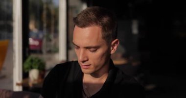 Kendine güveni tam bir adam kafede limonata içiyor.