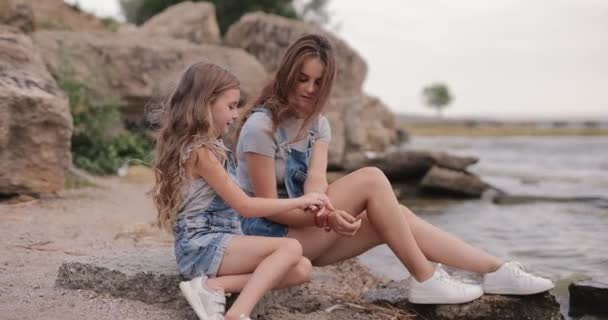 Two Sisters Throwing Stones Sea Sitting Beach — Vídeo de Stock