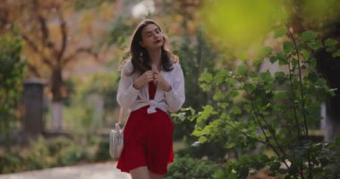 Woman walking along alley at the summer park, slow motion