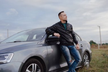 Tarlada arabasının yanında duran yakışıklı şık adam.