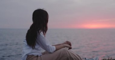 Genç kız deniz manzarasına bakıyor ve bulutlu bir günde düşünüyor