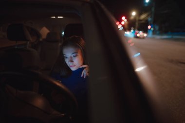 Geceleri arabada cep telefonu kullanan bir kadın.