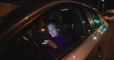 Geceleri arabada cep telefonu kullanan bir kadın.