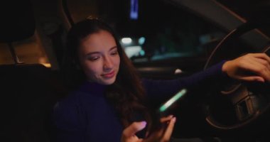 Geceleri arabada cep telefonu kullanan bir kadın.