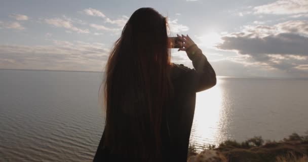 女子在海面上的山上拍摄日落的惊人景象 — 图库视频影像