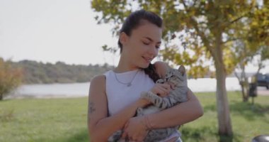 Gülümseyen kadın gri kedisiyle dışarıda oynuyor, ağır çekimde.