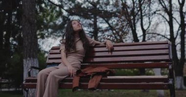 Sonbahar parkında bankta oturan kadın.