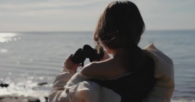Denize dürbünle bakan kadın turist, yavaş çekim.