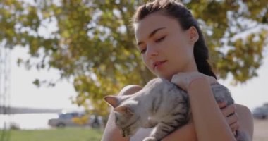 Gri kedisini kucaklayıp kucaklayan güzel bir kadın.